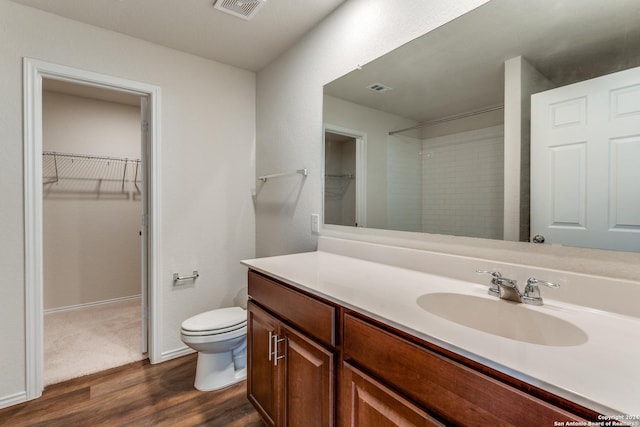 bathroom with hardwood / wood-style flooring, vanity, toilet, and a shower