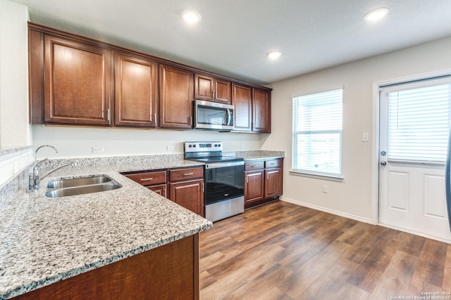 kitchen featuring sink, dark wood-type flooring, light stone countertops, and appliances with stainless steel finishes