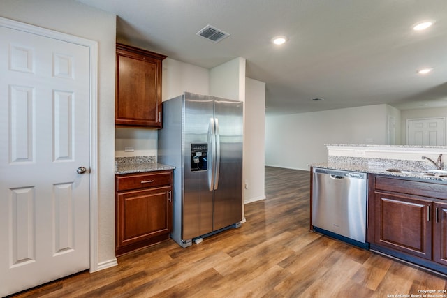 kitchen featuring light stone counters, appliances with stainless steel finishes, dark wood-type flooring, and sink