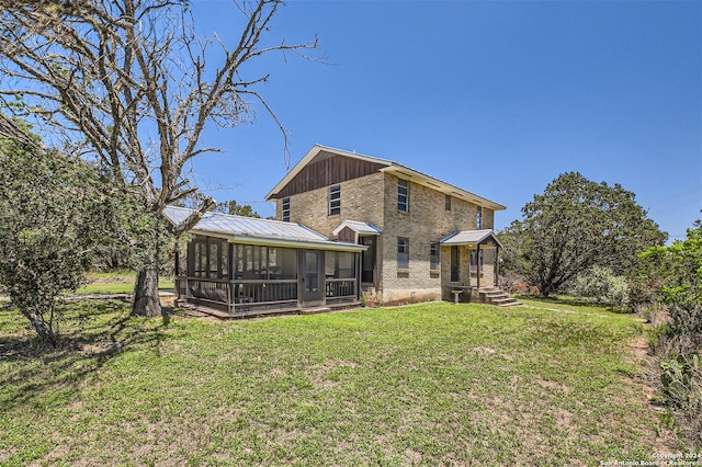 rear view of house with a yard and a sunroom