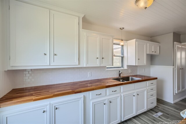 kitchen with butcher block countertops, white cabinetry, sink, and decorative light fixtures