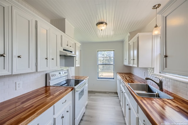 kitchen featuring white electric range oven, sink, white cabinetry, hanging light fixtures, and butcher block counters