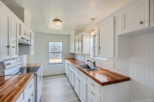 kitchen featuring pendant lighting, electric range, sink, and wooden counters