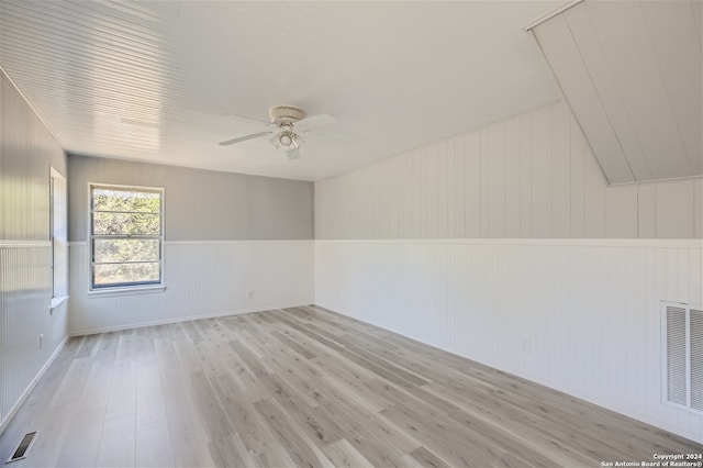 empty room with ceiling fan, vaulted ceiling, and light wood-type flooring