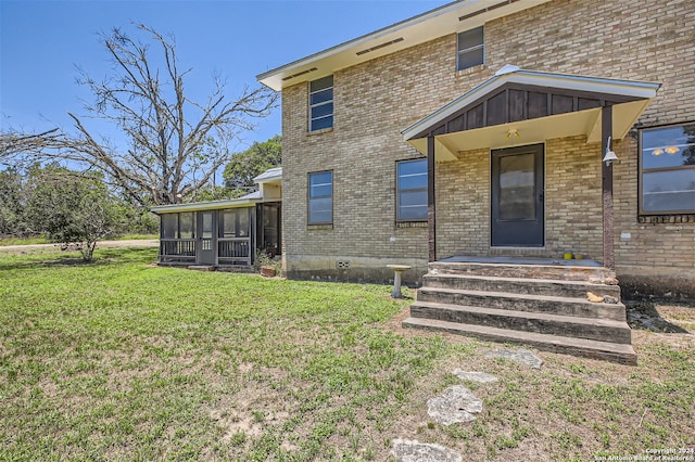 back of property with a lawn and a sunroom