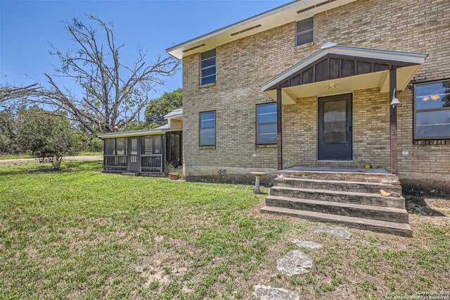 back of property with a lawn and a sunroom