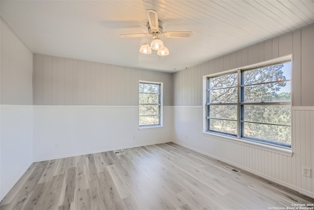 empty room with ceiling fan and light hardwood / wood-style flooring