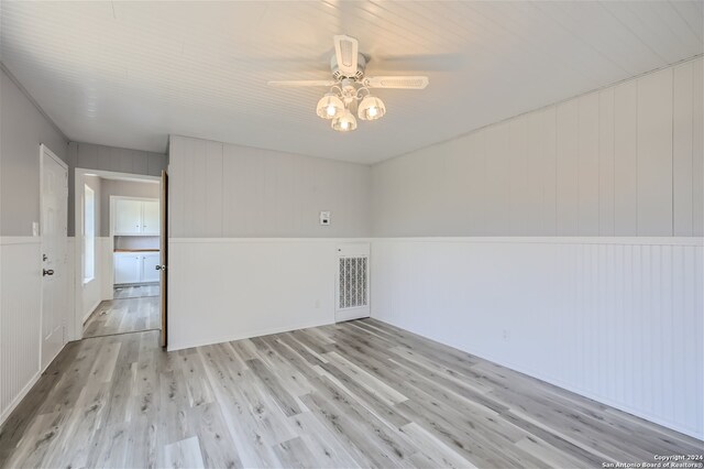 unfurnished room featuring ceiling fan, wooden walls, and light hardwood / wood-style flooring