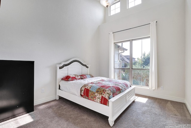 bedroom featuring dark carpet, a high ceiling, and multiple windows