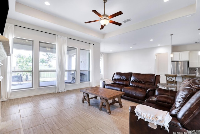 living room featuring ceiling fan and a raised ceiling