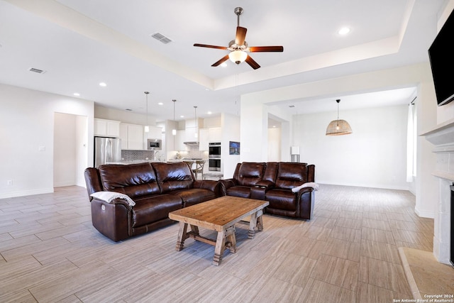 living room with a tray ceiling and ceiling fan