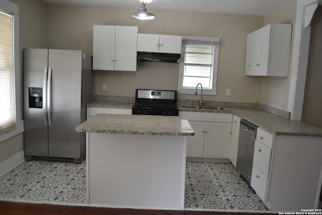 kitchen featuring white cabinets, sink, light stone countertops, appliances with stainless steel finishes, and a kitchen island