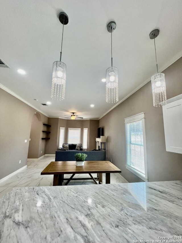 unfurnished dining area featuring ceiling fan with notable chandelier and ornamental molding