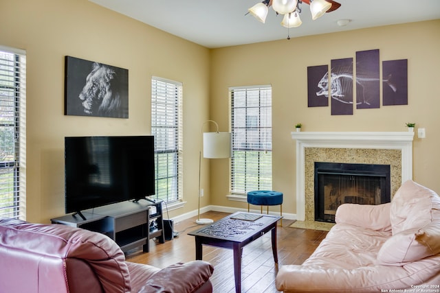 living area with ceiling fan, wood finished floors, baseboards, and a premium fireplace