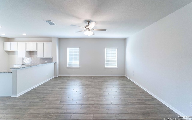 unfurnished living room with baseboards, ceiling fan, visible vents, and wood finished floors