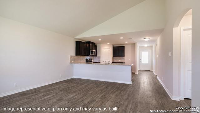 kitchen featuring kitchen peninsula, backsplash, high vaulted ceiling, and dark wood-type flooring