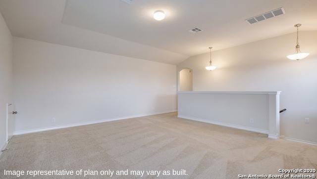 empty room with light colored carpet and vaulted ceiling