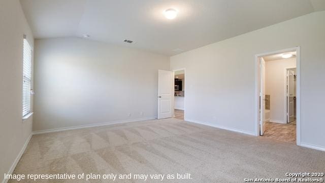 unfurnished room featuring light colored carpet and vaulted ceiling