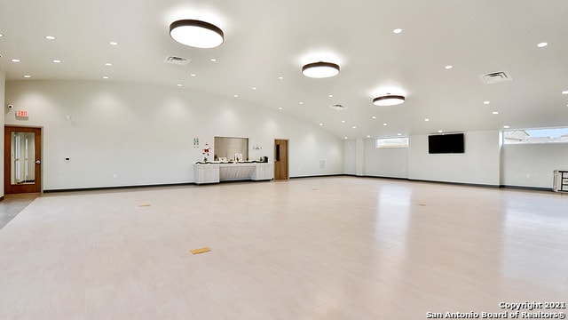 spare room featuring light hardwood / wood-style floors and lofted ceiling