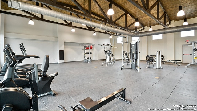 exercise room featuring high vaulted ceiling and wooden ceiling