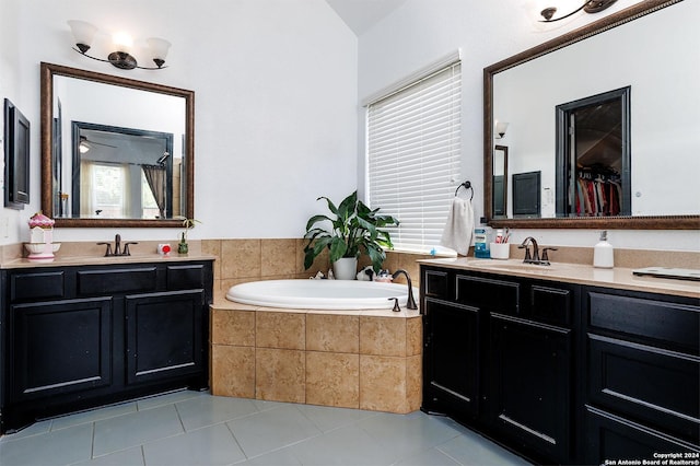 bathroom with tile patterned flooring, vanity, and a relaxing tiled tub