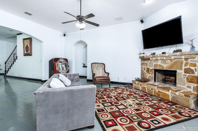 tiled living room with a stone fireplace, vaulted ceiling, and ceiling fan