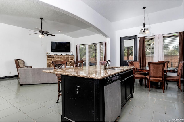 kitchen with sink, dishwasher, a kitchen island with sink, light stone countertops, and decorative light fixtures