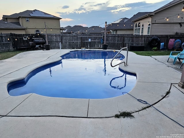 pool at dusk with a patio area