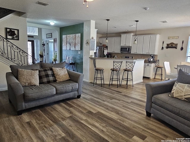 living room with a textured ceiling and dark wood-type flooring