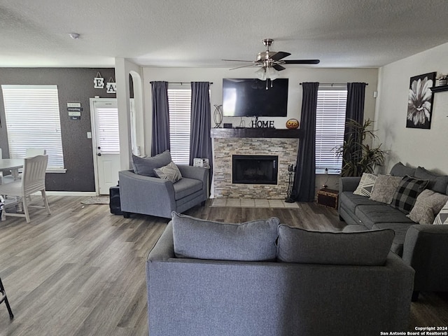 living room featuring ceiling fan, a textured ceiling, hardwood / wood-style flooring, and a fireplace