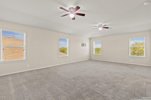 carpeted empty room featuring ceiling fan, lofted ceiling, and a wealth of natural light