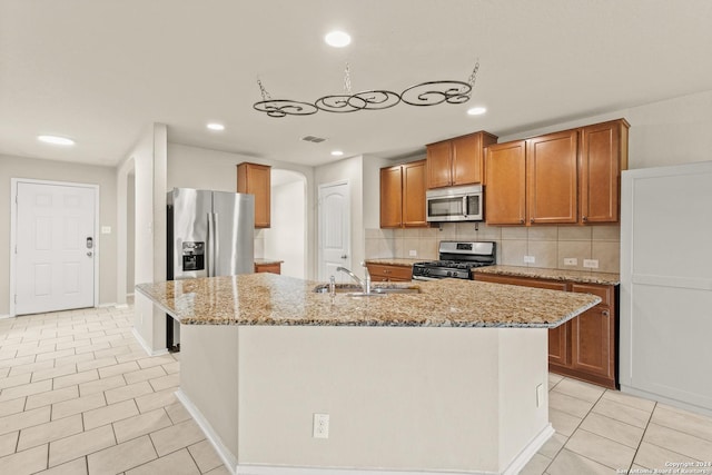 kitchen featuring a kitchen island with sink, sink, light tile patterned floors, and stainless steel appliances