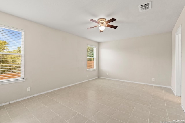 tiled empty room with a wealth of natural light and ceiling fan