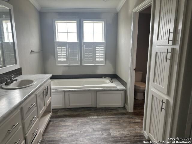 bathroom featuring ornamental molding, vanity, hardwood / wood-style floors, toilet, and a bathing tub