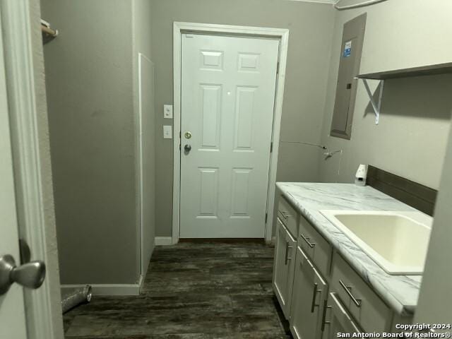 laundry area with electric panel, sink, and dark hardwood / wood-style floors