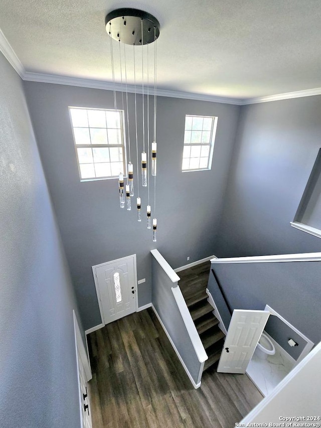 stairs with wood-type flooring, crown molding, and a textured ceiling