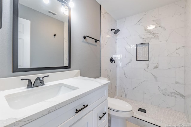 bathroom featuring toilet, vanity, and tiled shower