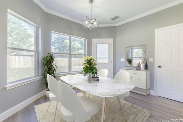 dining space featuring an inviting chandelier, crown molding, and light wood-type flooring