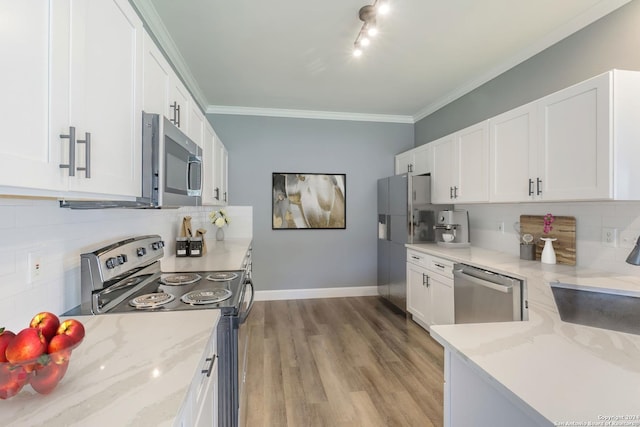 kitchen featuring crown molding, white cabinets, appliances with stainless steel finishes, and light stone counters