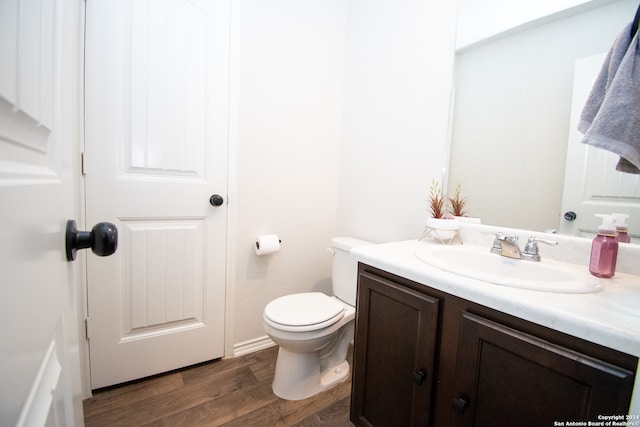 bathroom with hardwood / wood-style flooring, toilet, and vanity