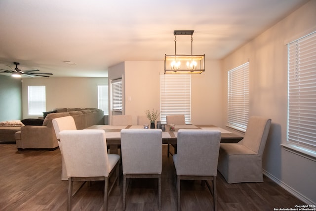 dining space with ceiling fan with notable chandelier and dark hardwood / wood-style flooring