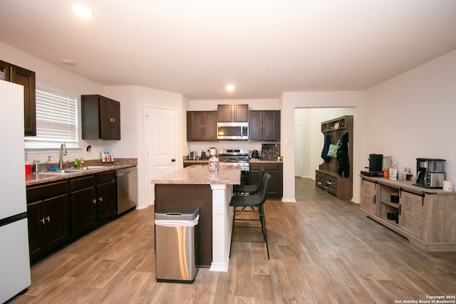 kitchen with a center island, light hardwood / wood-style floors, stainless steel appliances, a breakfast bar, and sink