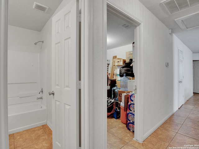 hall featuring light tile patterned floors and a textured ceiling