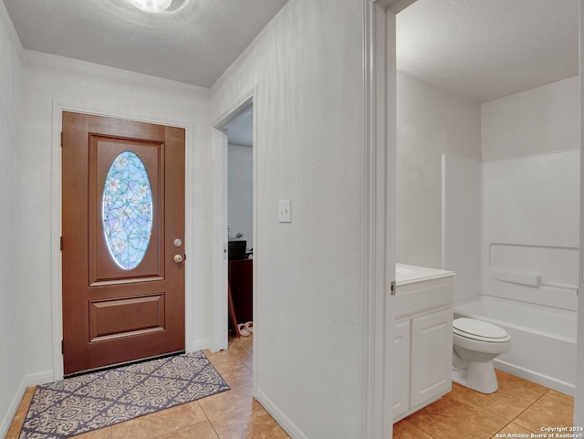 entryway featuring light tile patterned flooring and a textured ceiling