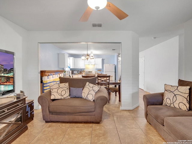 tiled living room with ceiling fan with notable chandelier