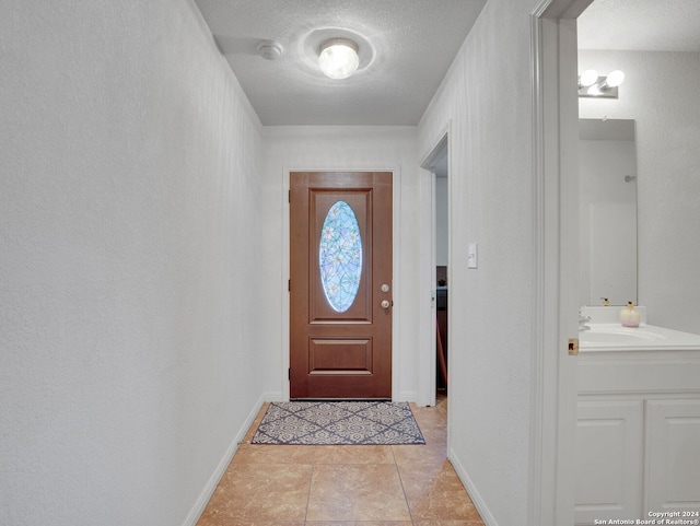 entryway featuring a textured ceiling, light tile patterned flooring, and sink