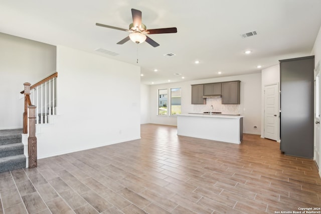 unfurnished living room with ceiling fan, sink, and light hardwood / wood-style floors