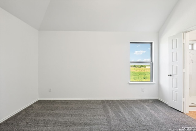 unfurnished room featuring dark carpet and vaulted ceiling