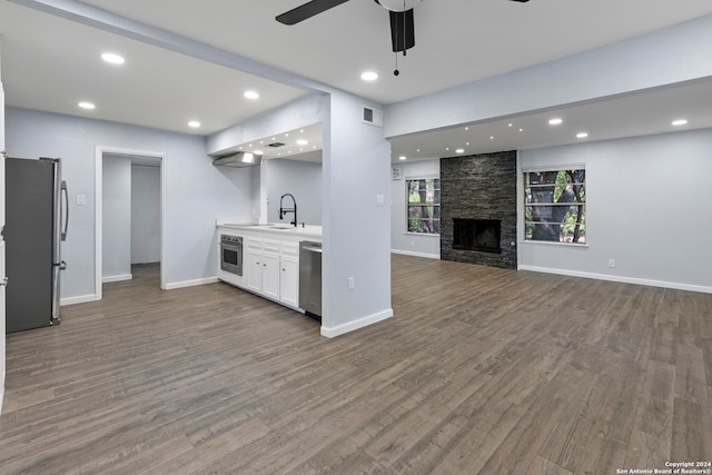 interior space with a stone fireplace, ceiling fan, hardwood / wood-style floors, and sink