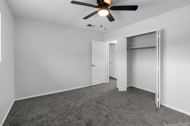 unfurnished bedroom featuring dark colored carpet, a closet, and ceiling fan